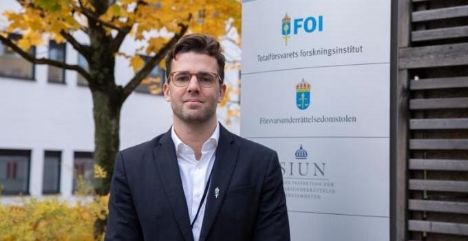 Porträtt av Martin Tavander framför FOI-skylt.