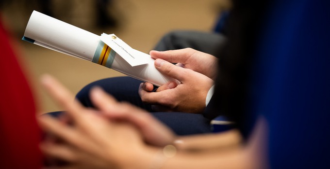 hands holding a rolle up diploma