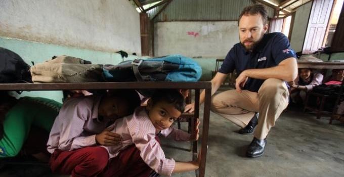 A representative from and international organisation together with children in a house in the Caribbean.