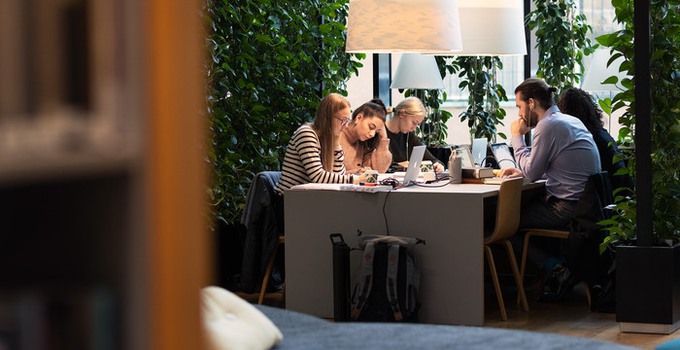 Interiör från Anna Lindh-biblioteket där studenter studerar vid ett bord. 