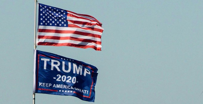 Amerikans flagga och Trump 2020 flagga mot blå himmel.