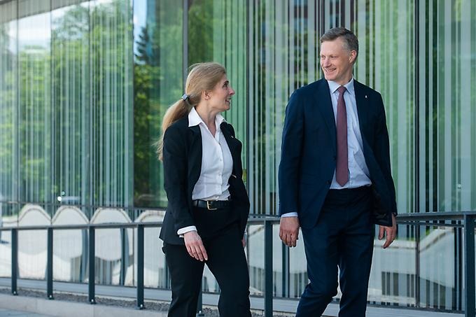 Två personer går och talar med varandra utanför Försvarshögskolan.