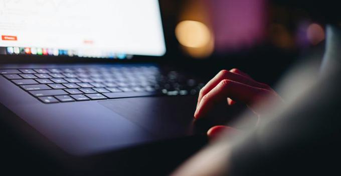 Närbild på en hand och en dators tangentbord.