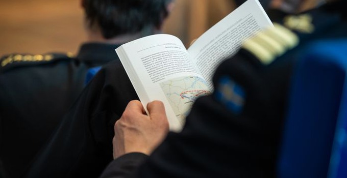 Man from behind holding an open book.