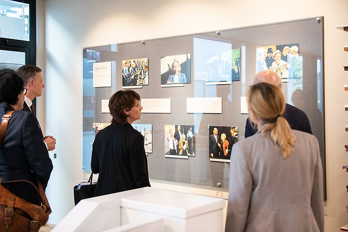 Matilda Ernkrans framför minnesvägg med fotografier av Anna Lindh.